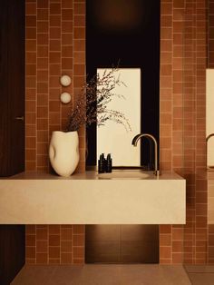 a white vase sitting on top of a counter next to a sink in a bathroom