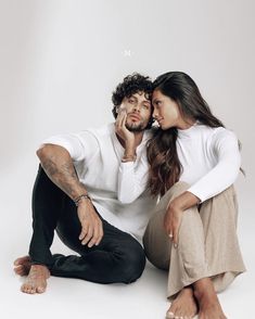 a man and woman sitting on the ground posing for a photo with their eyes closed