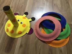 some paper plates are laying on the floor next to a toy giraffe and a ring