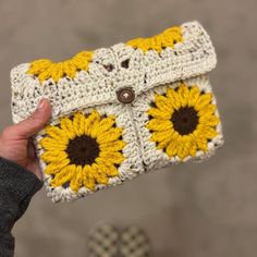 a hand holding a crocheted yellow and white purse with sunflowers on it