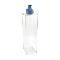 a blue vase sitting on top of a tall glass container in front of a white background