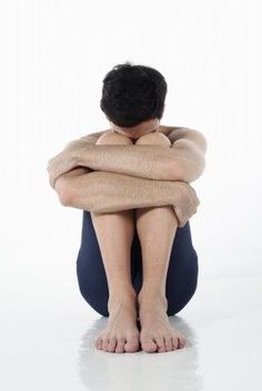 a man sitting on the ground with his arms folded over his head and legs crossed