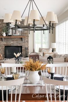 Golden stems in white pitcher and fall decorations on open concept kitchen table with white chairs. Fall Decor Ideas Kitchen, Early Fall Decorating, Front Porch Decor Fall