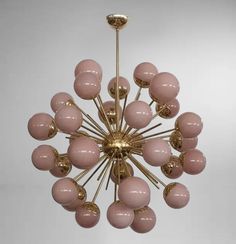 a pink and gold chandelier hanging from the ceiling in front of a white wall