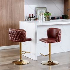 two brown leather barstools in front of a bar with white marble counter top