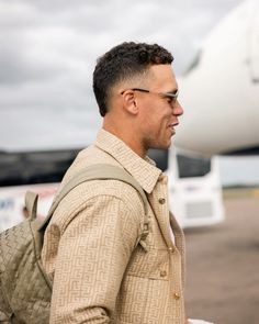 a man walking towards an airplane with a backpack on his back and one hand in the other's pocket