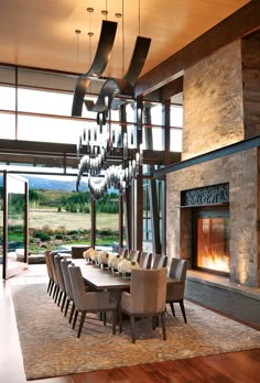 a dining room table with chairs and a chandelier in front of a fireplace