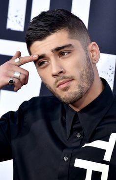 a man with a ring on his right hand and tattoos on his left arm, wearing a black shirt