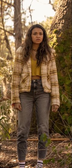 a woman standing in the woods with her hands on her hips