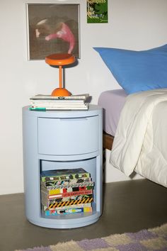 there is a small blue table with magazines on it and a lamp next to it