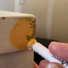 someone is painting the side of a wooden block with yellow and white paint on it