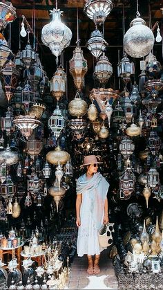 a woman standing in front of a display of hanging lamps