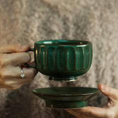 two hands holding a green cup and saucer