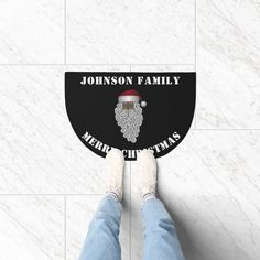 a person standing on top of a tile floor next to a white wall with a black sign that says, johnson's family merry christmas