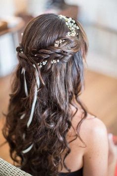 the back of a woman's head with long hair and flowers in her hair