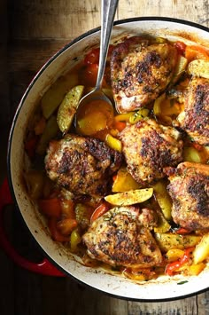 a pot filled with chicken and vegetables on top of a wooden table