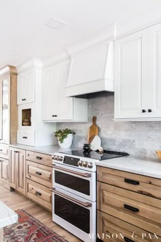 a kitchen with white cabinets and marble counter tops, an oven and stove top in the center