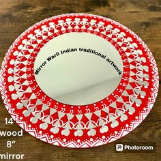 a red and white plate sitting on top of a wooden table next to a mirror