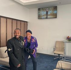 a man and woman posing for a photo in an office setting with chairs, couches and paintings on the wall