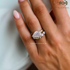 a woman's hand with a diamond ring on top of her finger and the other hand holding an engagement ring