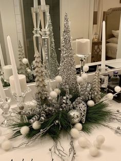 a white table topped with lots of candles and christmas tree decorations on top of it