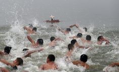 many people are in the water and one person is on a small boat behind them