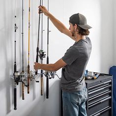 a man is fixing fishing rods on the wall