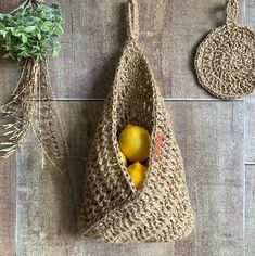 a crocheted bag with two lemons in it next to a potted plant