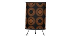 an orange and black lamp shade with circles on it's side, against a white background