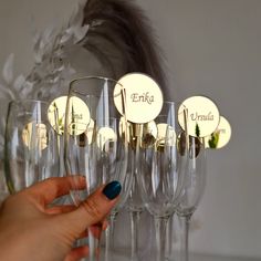 a woman is holding a wine glass in front of many glasses with names on them