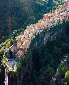 an aerial view of a village on the edge of a cliff, surrounded by trees