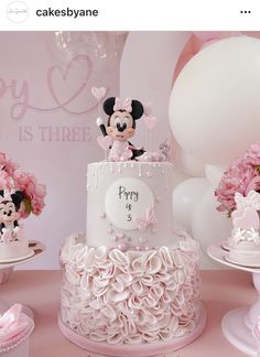 there is a birthday cake with minnie mouse on it and pink flowers in the background