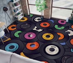 a room filled with lots of different colored records on the floor next to a window