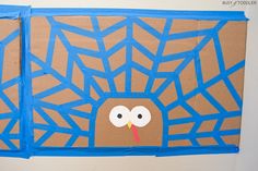 a turkey made out of cardboard sitting on top of a white wall with blue tape