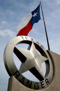 the texas rangers logo is on top of a building with a flag flying above it