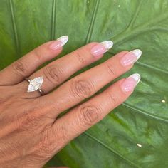 a woman's hand with pink and white manicured nails holding a diamond ring