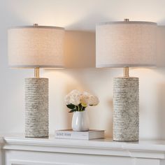 two vases with flowers sit on top of a mantel