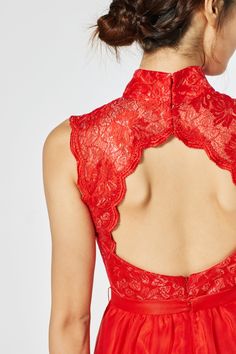 a woman wearing a red dress with an open back and lace detailing on the neck