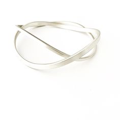 This solid sterling silver curved double interlinked bangle set sits beautifully on the hand and as it moves around creates interesting shapes. Each bangle has a matt/brushed finish with a square edge and are two different thicknesses which makes the design unique. This design is perfect to wear everyday. Metal: Solid Sterling Silver Width Widest bangle: 0.4 cm  Width: Narrower bangle: 0.25 cm Thickness: Widest bangle: 0.2 cm Thickness: Narrower bangle: 0.25 cm Profile: Square This listing is fo Sterling Silver Bracelet With A Modern Twist, Modern Silver Flexible Bangle, Modern Twist Sterling Silver Bangle Bracelet, Modern Twist Sterling Silver Bracelet, Silver Bangle With A Modern Twist, Modern Twist Silver Bracelets, Sterling Silver Bangle With A Modern Twist, Modern Twist Flexible Bangle As Gift, Modern Twist Silver Bangle Bracelets