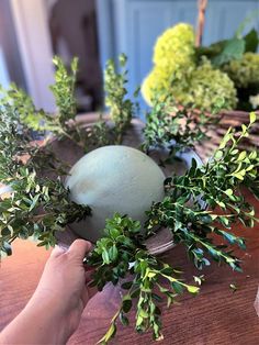 a person is arranging greenery on a table