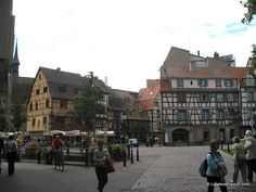 many people are walking around in an old town square with half - timbered buildings