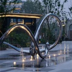 an artistic sculpture in the middle of a city square with water shooting from it's sides