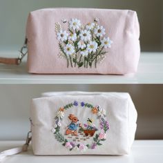 two bags with embroidered flowers on them, one in pink and the other in white