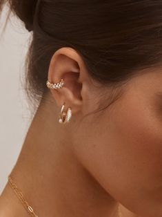 a close up of a woman wearing gold ear cuffs and a diamond ring on her left ear