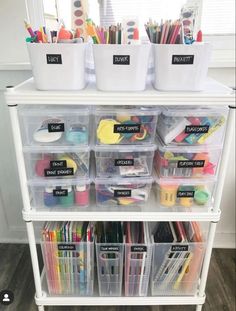 a white shelf filled with lots of plastic containers and bins full of art supplies