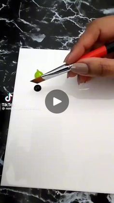 someone is cutting out a piece of paper with scissors and some glue on top of it