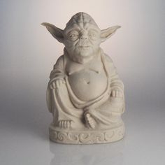 a statue of yoda is sitting on a white surface