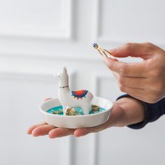 a person is holding a small bowl with a llama in it and gold decorations