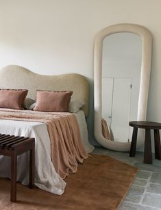 a bed sitting next to a mirror in a bedroom