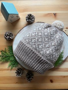 a knitted hat sitting on top of a wooden table next to pine cones and other decorations